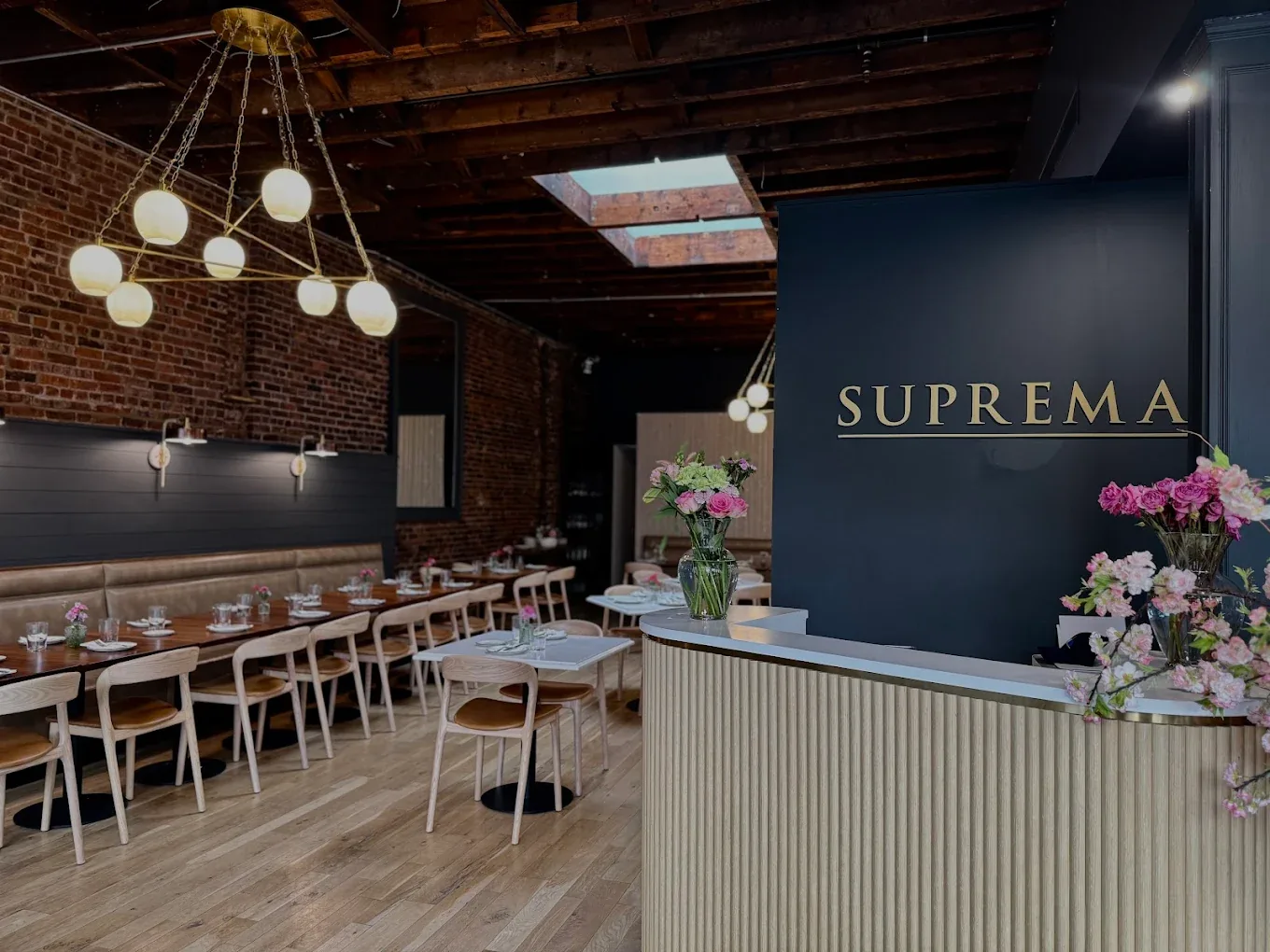 Suprema's dining room: navy walls, gold lettering, brick and a skylight
