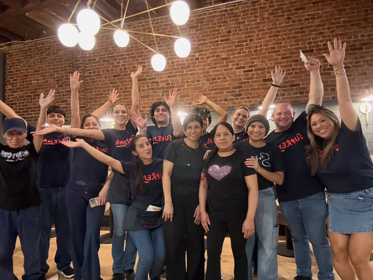 The Suprema crew together in the dining room, arms in the air